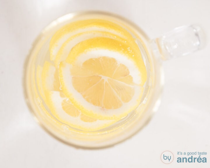 A carafe filled with water and lemon on a white surface