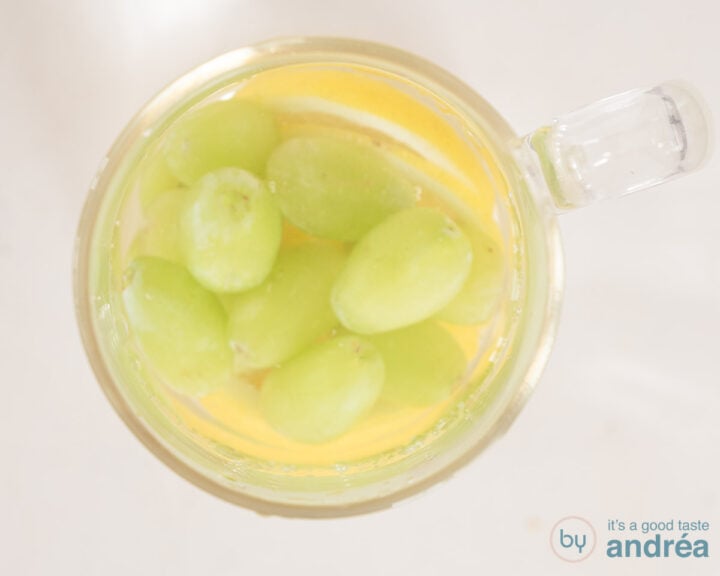 A carafe filled with water, lemon and grapes