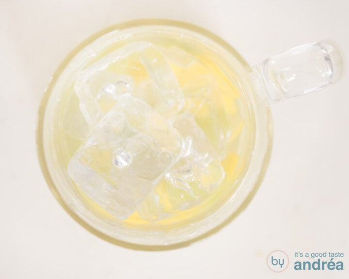 A carafe with water, fruit and ice on a white surface