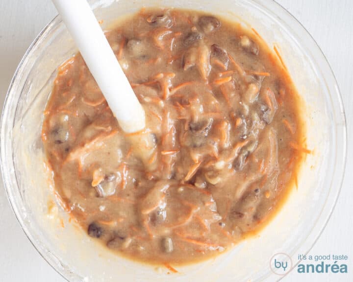 A glass bowl with carrot cake batter mixed together.