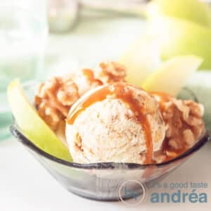 A square photo of a bowl with ice cream, apples, walnuts on a white background