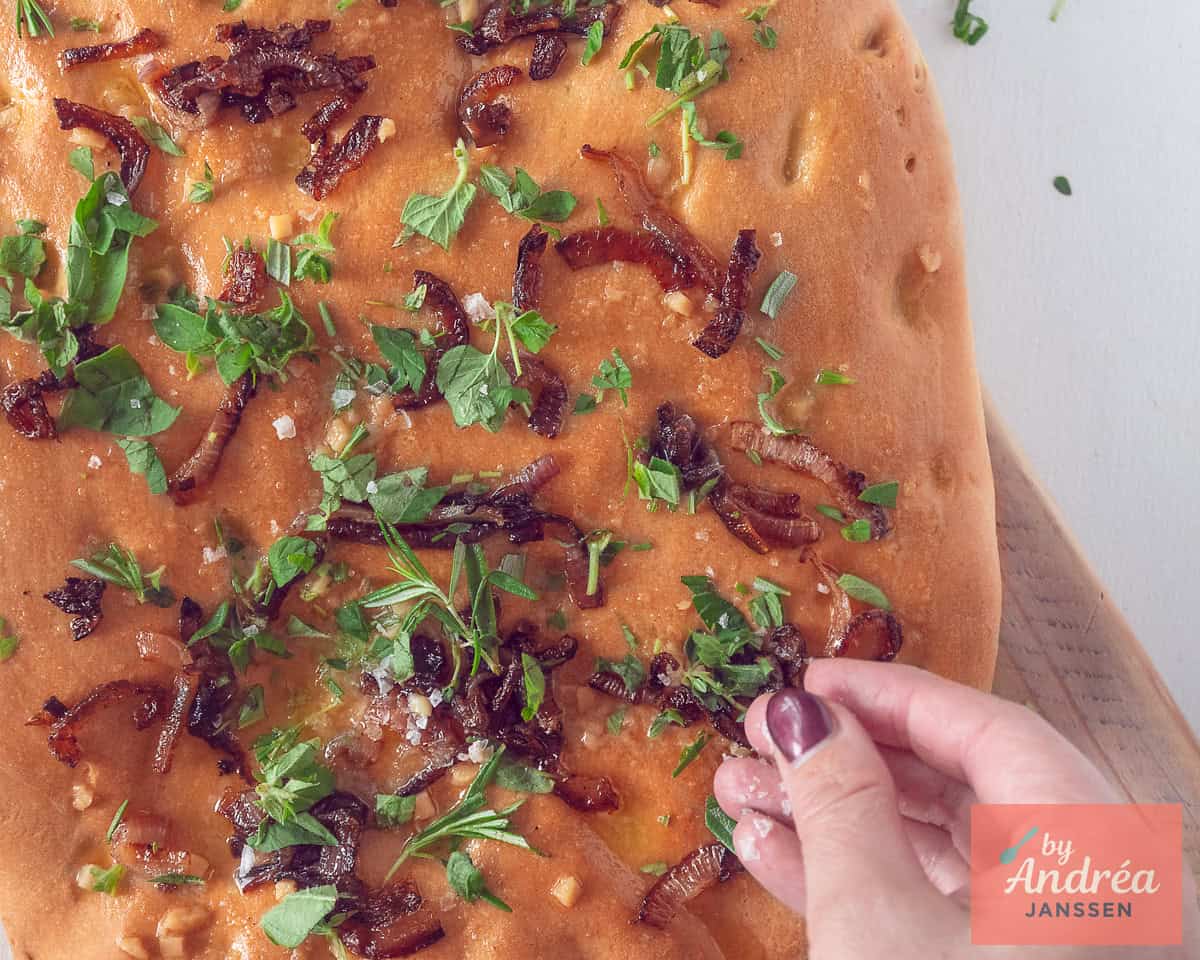 Kruiden worden verdeeld over de focaccia