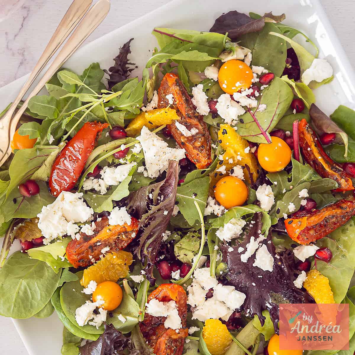A square photo of a salad with feta, golden berries, sun-dried tomatoes and orange