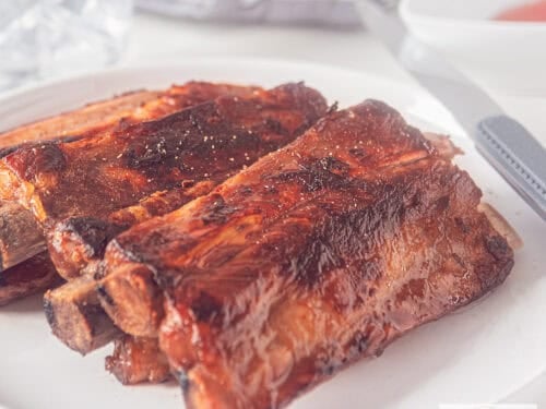 A square photo of a plate with a stack of honey kecap whisky ribs.