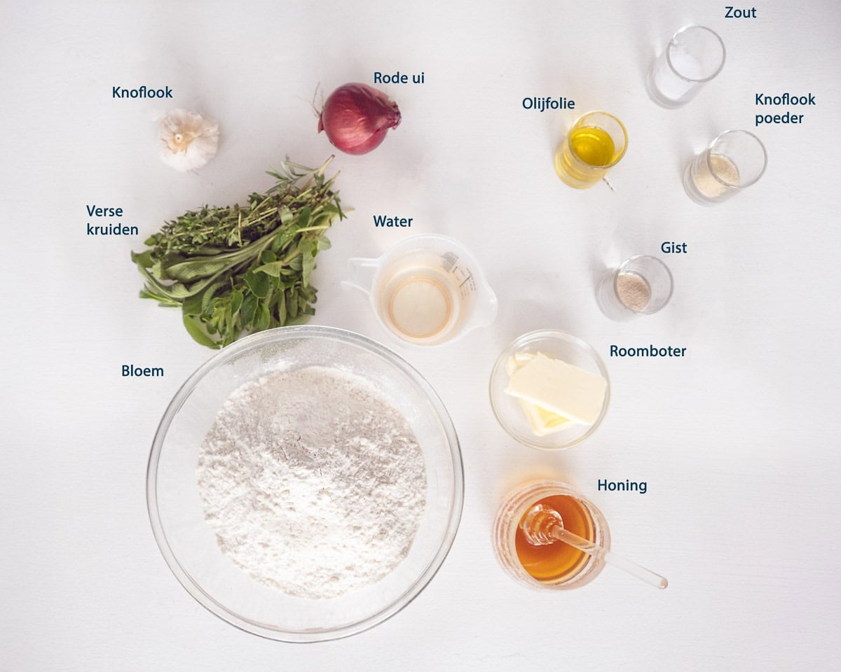 Ingredienten Focaccia Met Kruidenboter En Rode Ui op een witte ondergrond met tekstbeschrijving