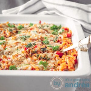 A macaroni casserole in a white dish. In the background a gray and white striped towel