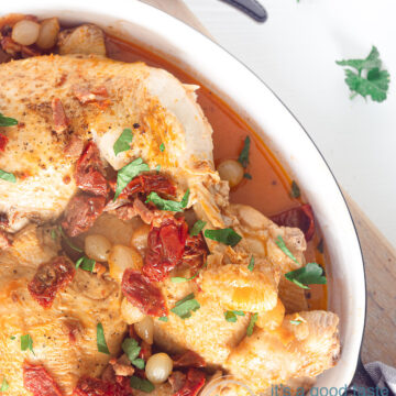 a casserole with coq au vin blanc, bacon and tomatoes