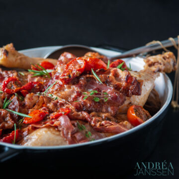 a casserole with coq au vin blanc, bacon and tomatoes