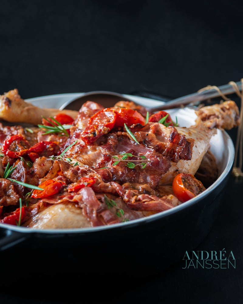 a casserole with coq au vin blanc, bacon and tomatoes
