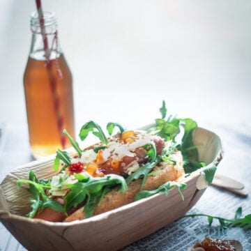 a bamboo container with a Hot dog de luxe and a bottle with a drink