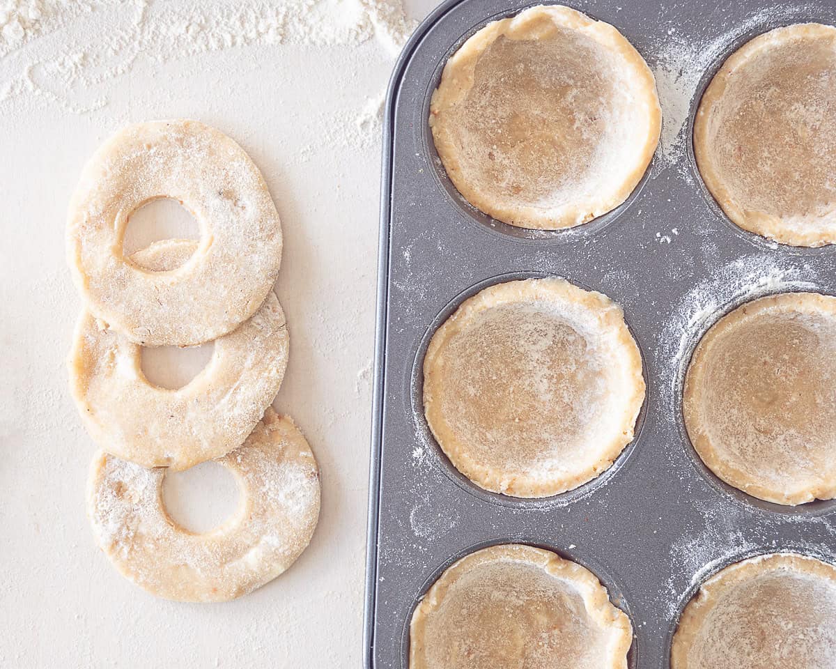 Some cupcake holes filled with dough that forms a bowl. On the left some dough toppings that are already prepared