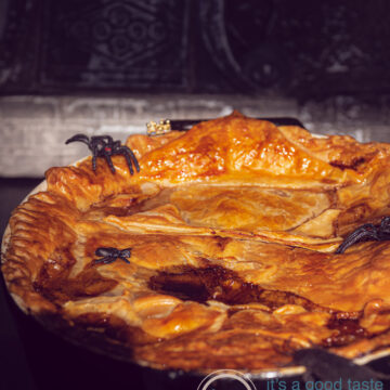 A Pie filled with stewed beef, Guinness, vegetables and topped with puff pastry on a dark background. Dressed up in Halloween style.