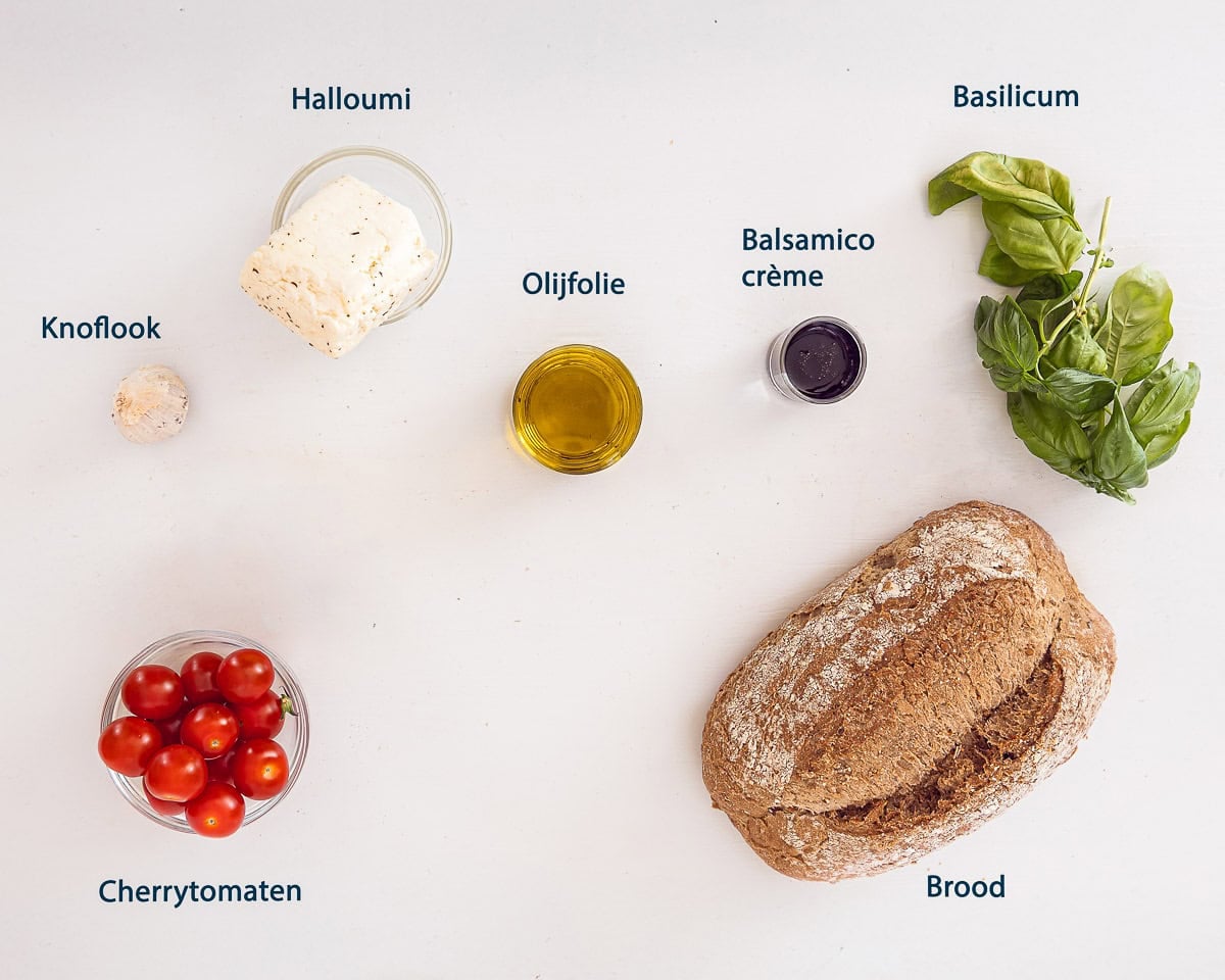 Ingredienten Halloumi Spiesjes Met Brood En Tomaat op een witte ondergrond met tekstbeschrijving