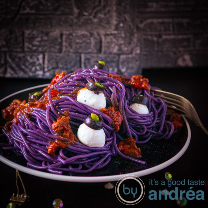 A square photo with a plate loaded with purple spaghetti bolognaise and mozzarella eyeballs.