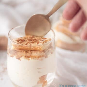 Two glasses with tiramisu, ladyfingers, licor 43 and cocoa. A golden spoon taking a bite off the dessert