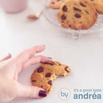 A square photo with half a cookie holding a hand. A white background. Top right a bowl with chocolate chip cookies.