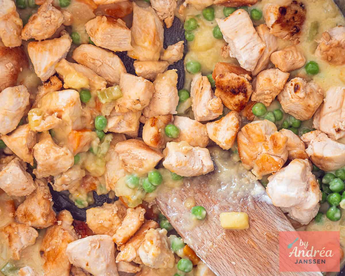 Creamy pot pie filling with chicken, peas and carrots in a skillet.