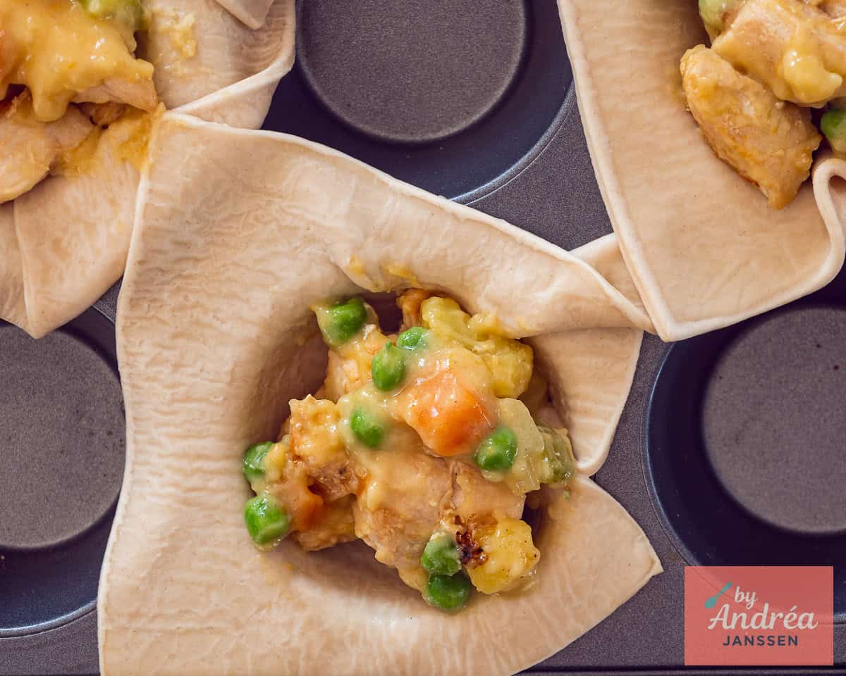 Savory pie dough pressed into a muffin tin to form pastry cups. Spoon filling into pastry cups in a muffin tray.