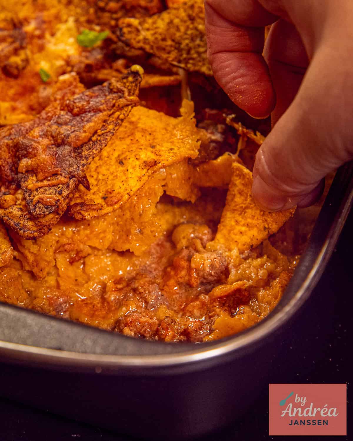 A hand taken a taco to get some spicy ground beef.