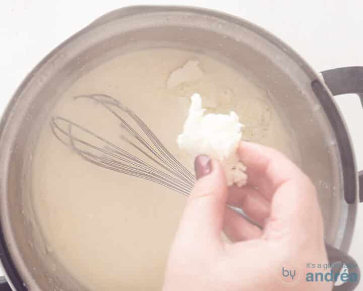 A cheese sauce in a saucepan to which mozzarella is added.