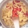 Pasta and tomatoes are mixed with the sauce in a pan.
