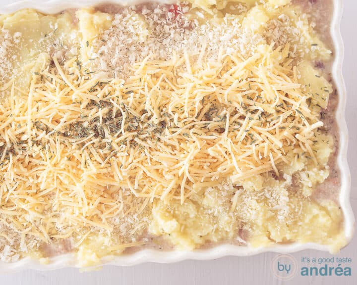 A width photo showing an oven dish with mashed potatoes sprinkled with panko, grated cheese and thyme