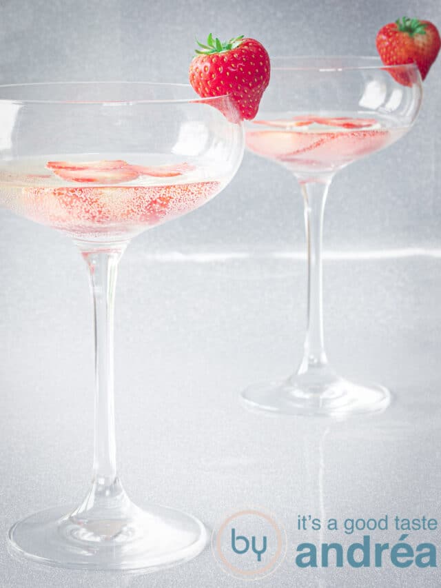 Two champagne bowls filled with strawberries and prosecco cocktail. A silver background