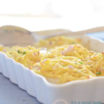 a white casserole dish on a blue background filled with cod fillets topped with potato gratin