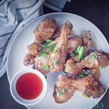 a white plate with chicken drumsticks in soy sauce