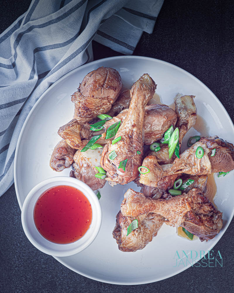 a white plate with chicken drumsticks in soy sauce