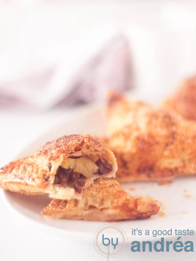a white plate with a sliced through apple turnover so you see the filling on a white background