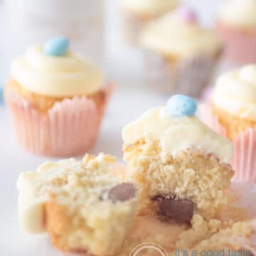 a bunch of easter cupcakes on a white background. One cupcake is halved and you can see a chocolate egg.