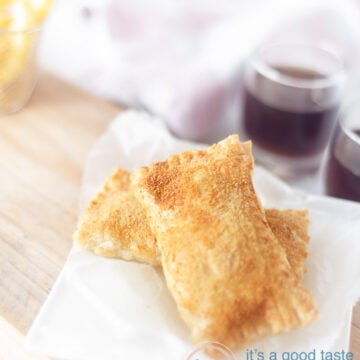 Two homemade cheese snacks on a white baking paper on a wooden board.