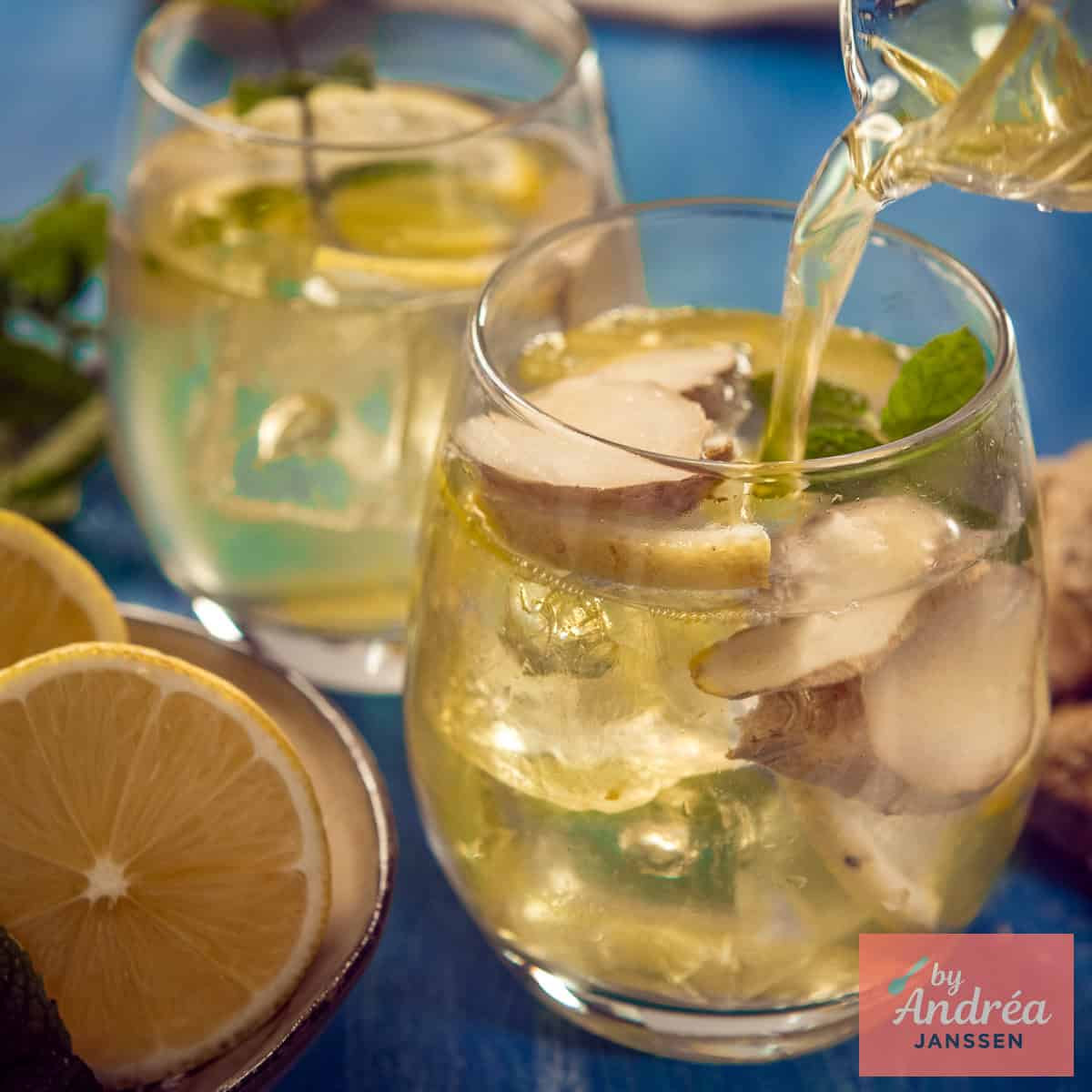 A square photo with two glasses filled with homemade ginger iced tea. One glass is being filled.