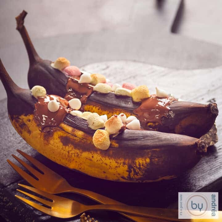 A square photo of two grilled bananas one after the other, flavored with whiskey, melted chocolate and marshmallows