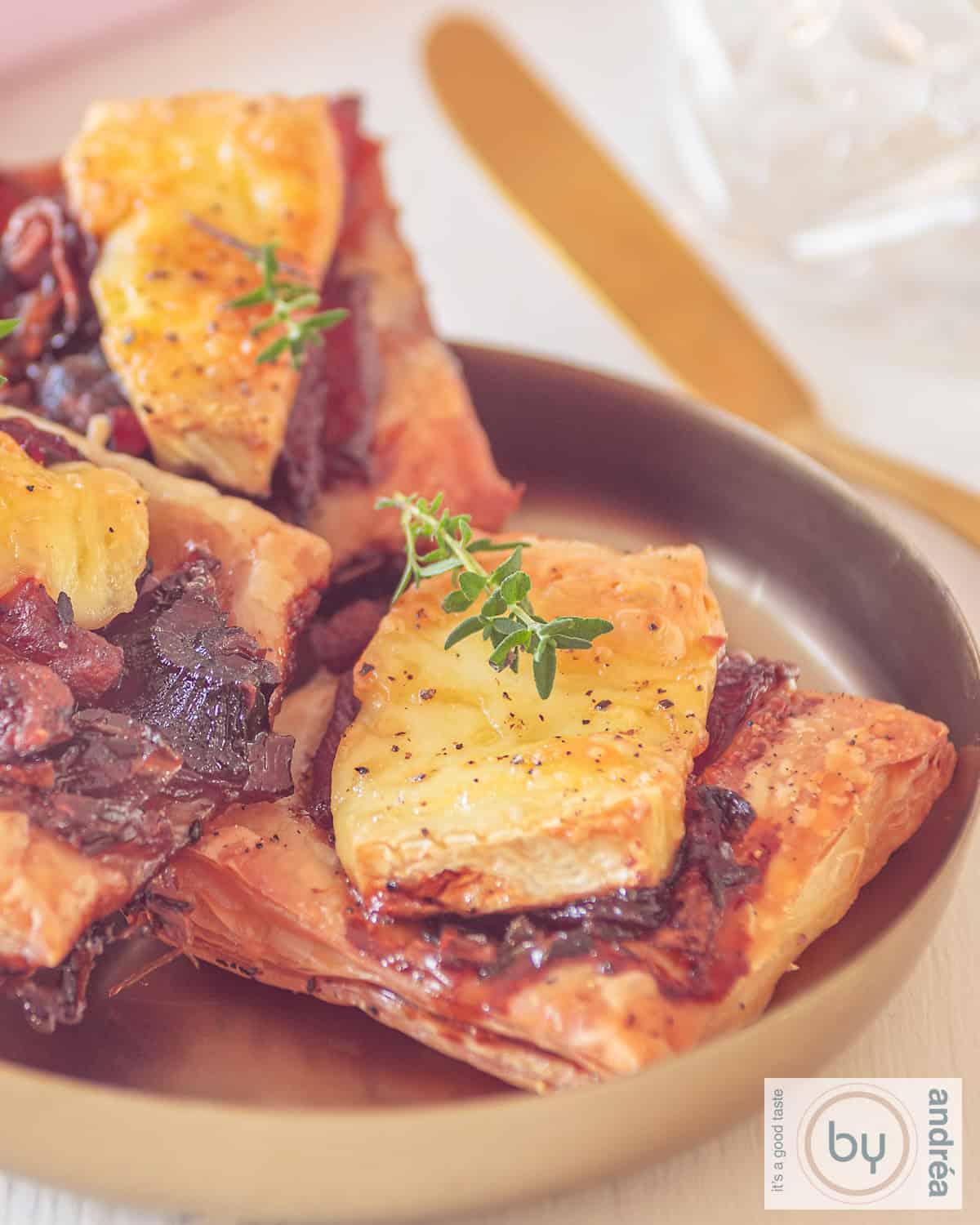 Een deel van een schaaltje met brie bladerdeeghapjes met gekarameliseerde ui en bacon.