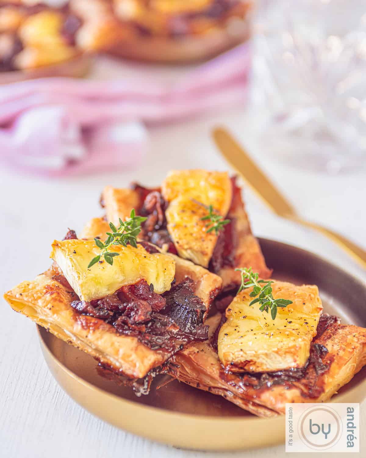 Een schaaltje met drie bladerdeeghapjes met brie, spekjes en gekarameliseerde uitjes.