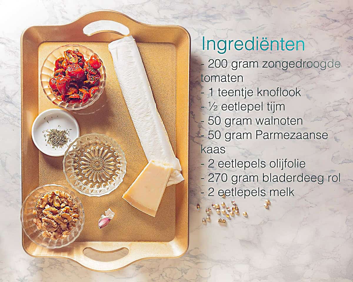 Ingredienten bladerdeeg kerstboom met rode pesto op een gouden dienblad. Een tekst omschrijving ernaast van de ingrediënten.