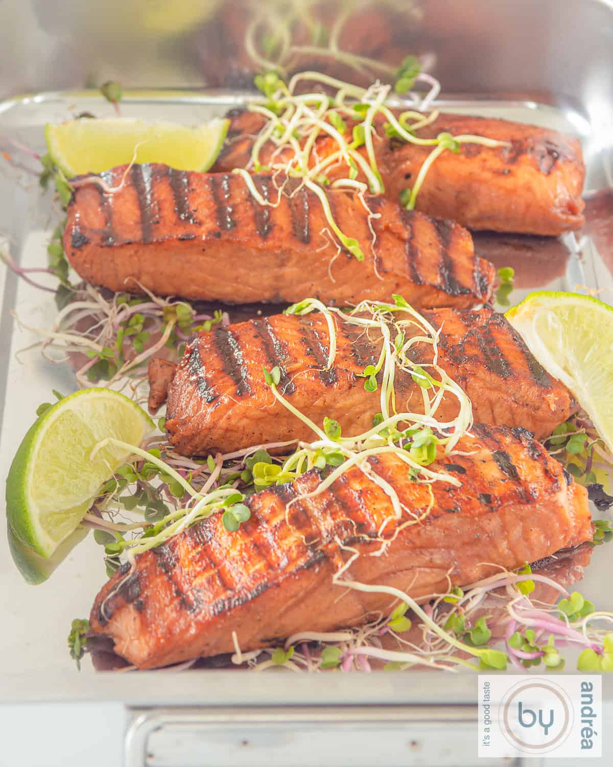 A platter of grilled and pickled salmon, 4 pieces with lime slices