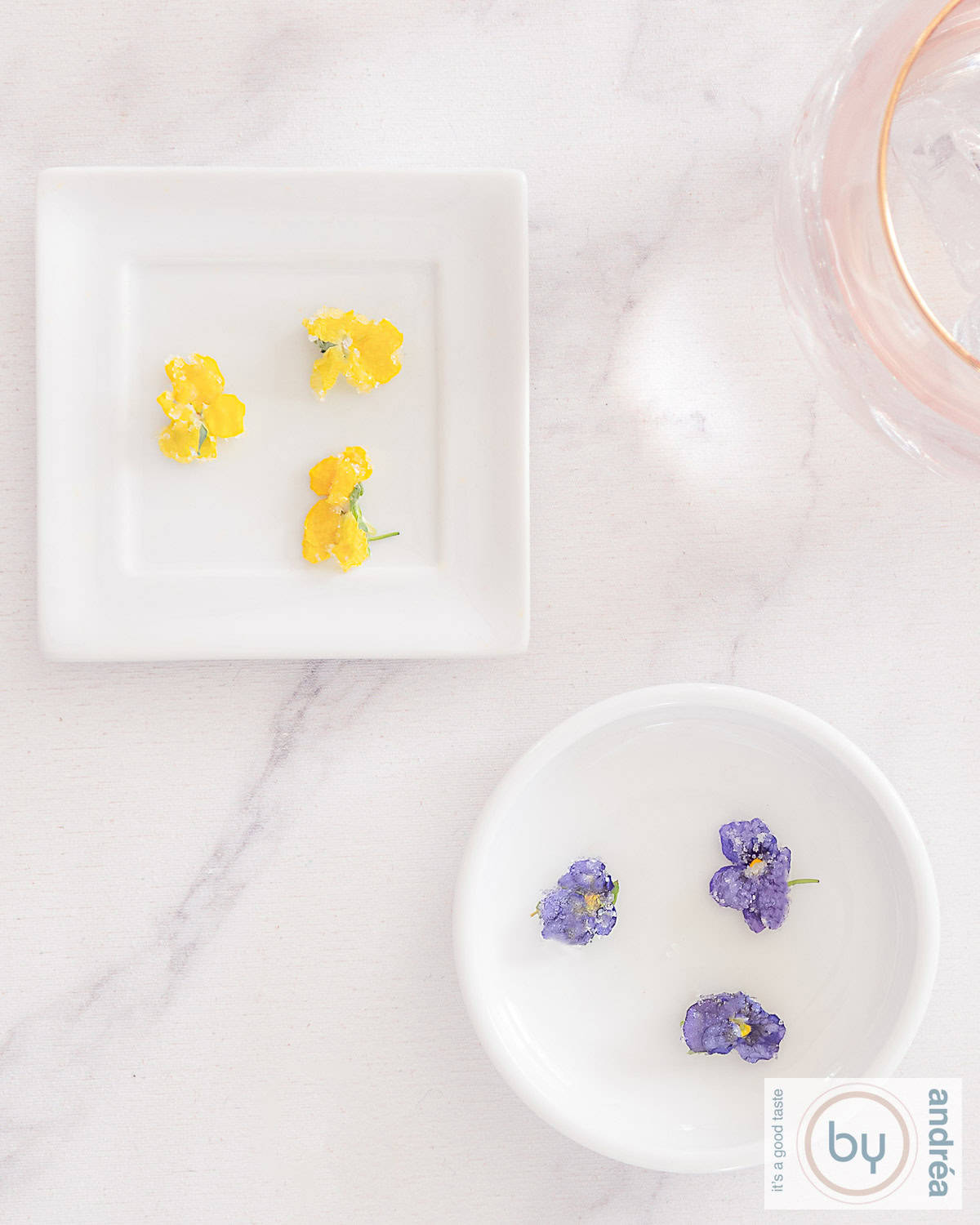 Een foto van bovenaf van twee schaaltjes met eetbare gesuikerde bloemen.