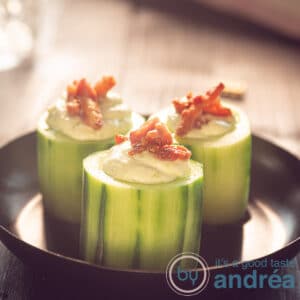 a square photo of cucumber bite appetizers on a black plate