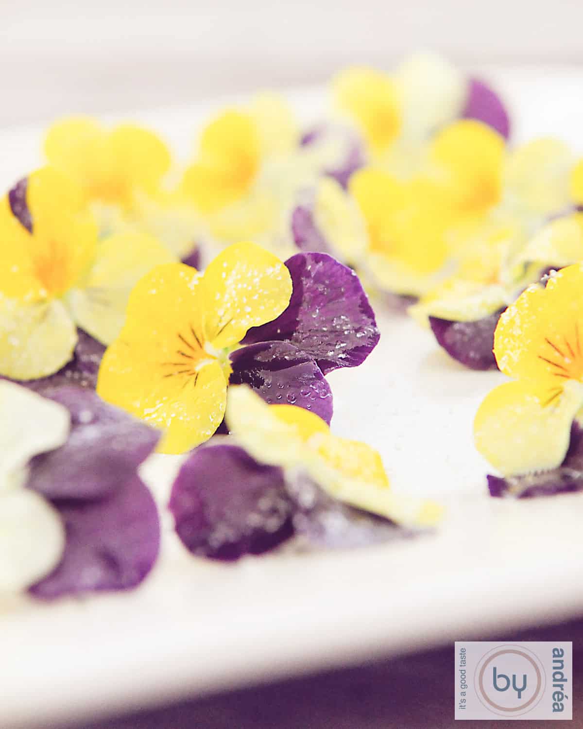 Een hoogtefoto van een wit bord met eetbare bloemen, viooltjes