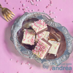 A square picture with a silver tray with red velvet fudge. A pink background