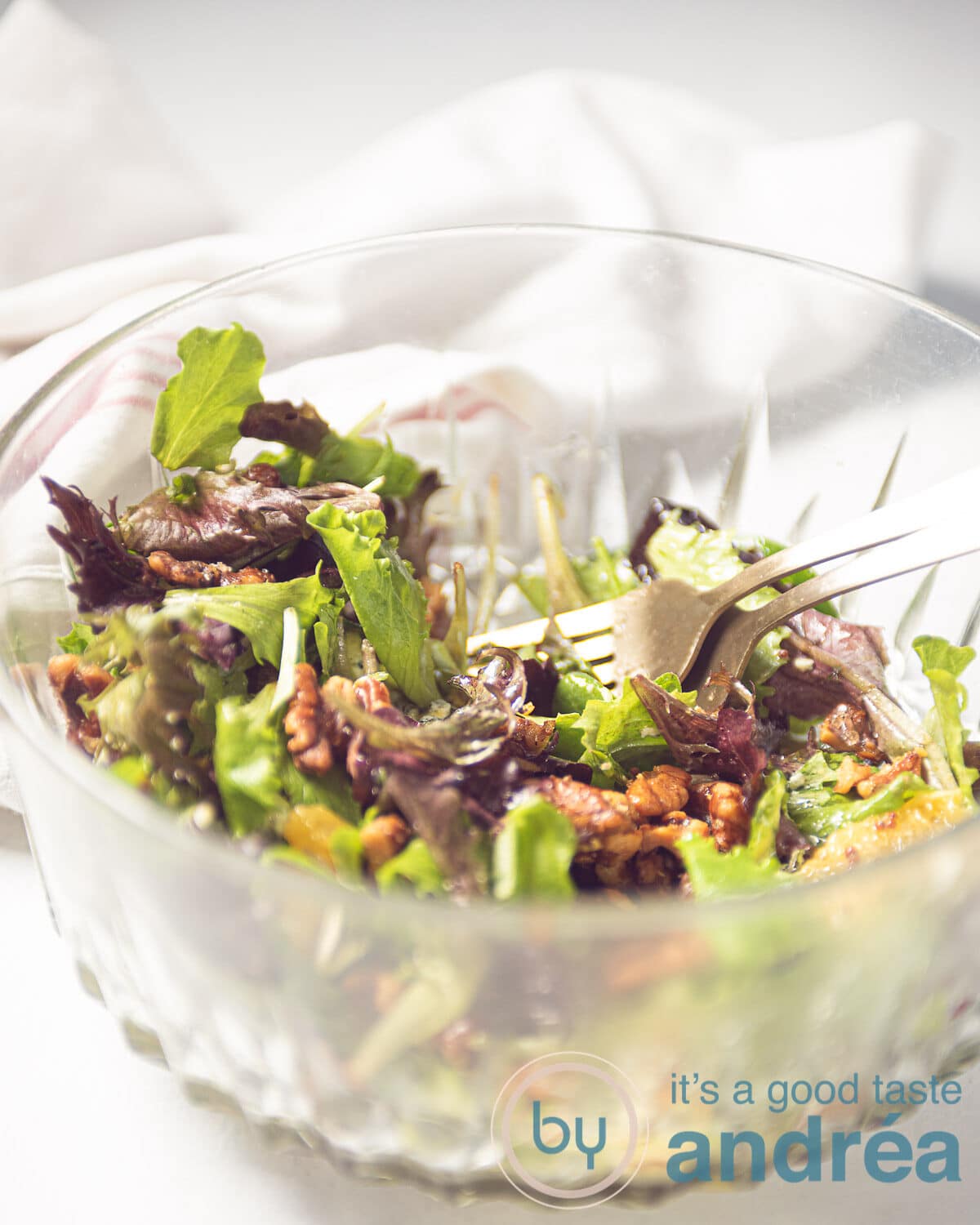 a glass bowl filled with a salad with oranges, walnuts, and blue cheese