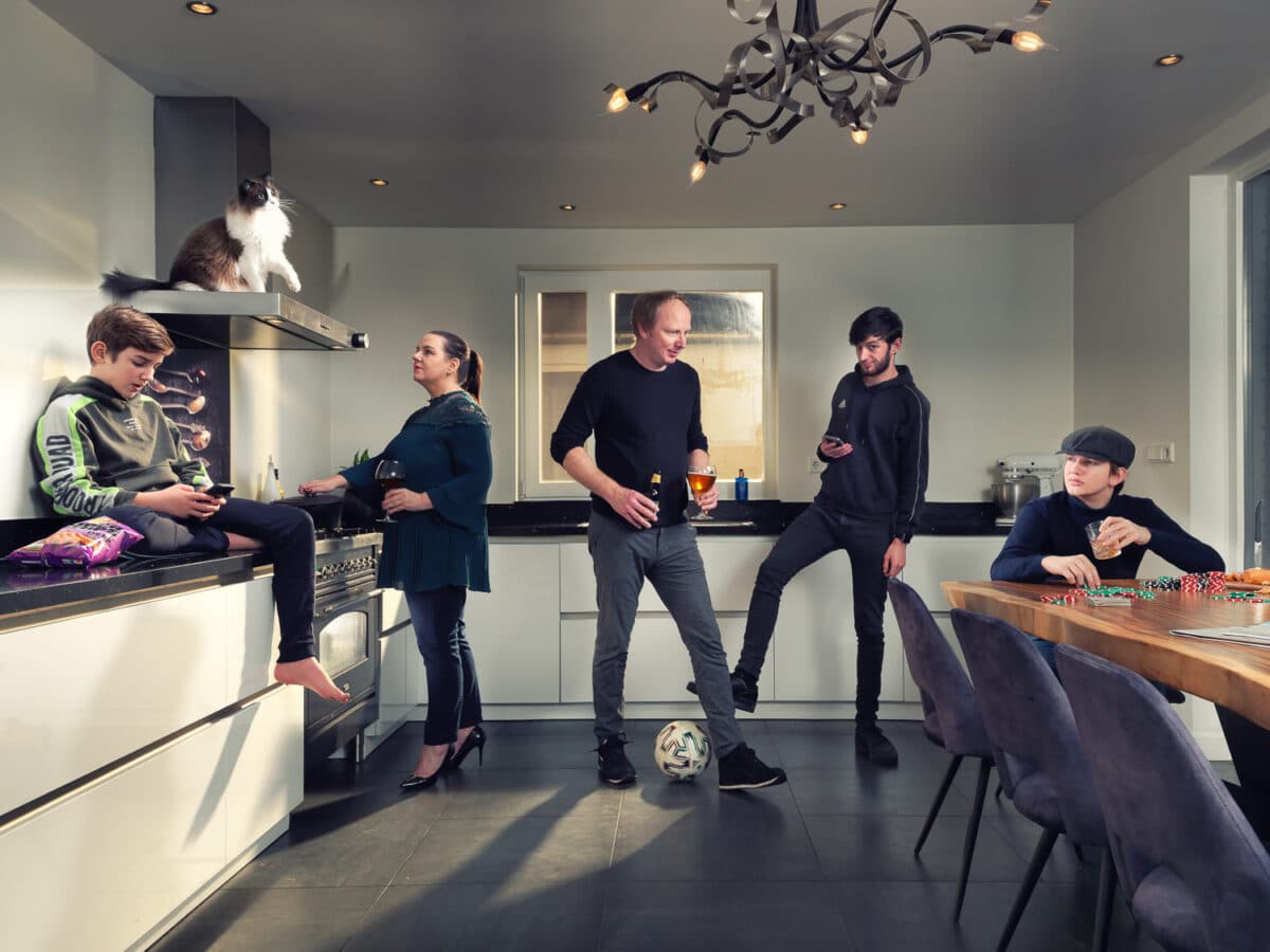 5 personen op foto die in een keuken staan en een kat