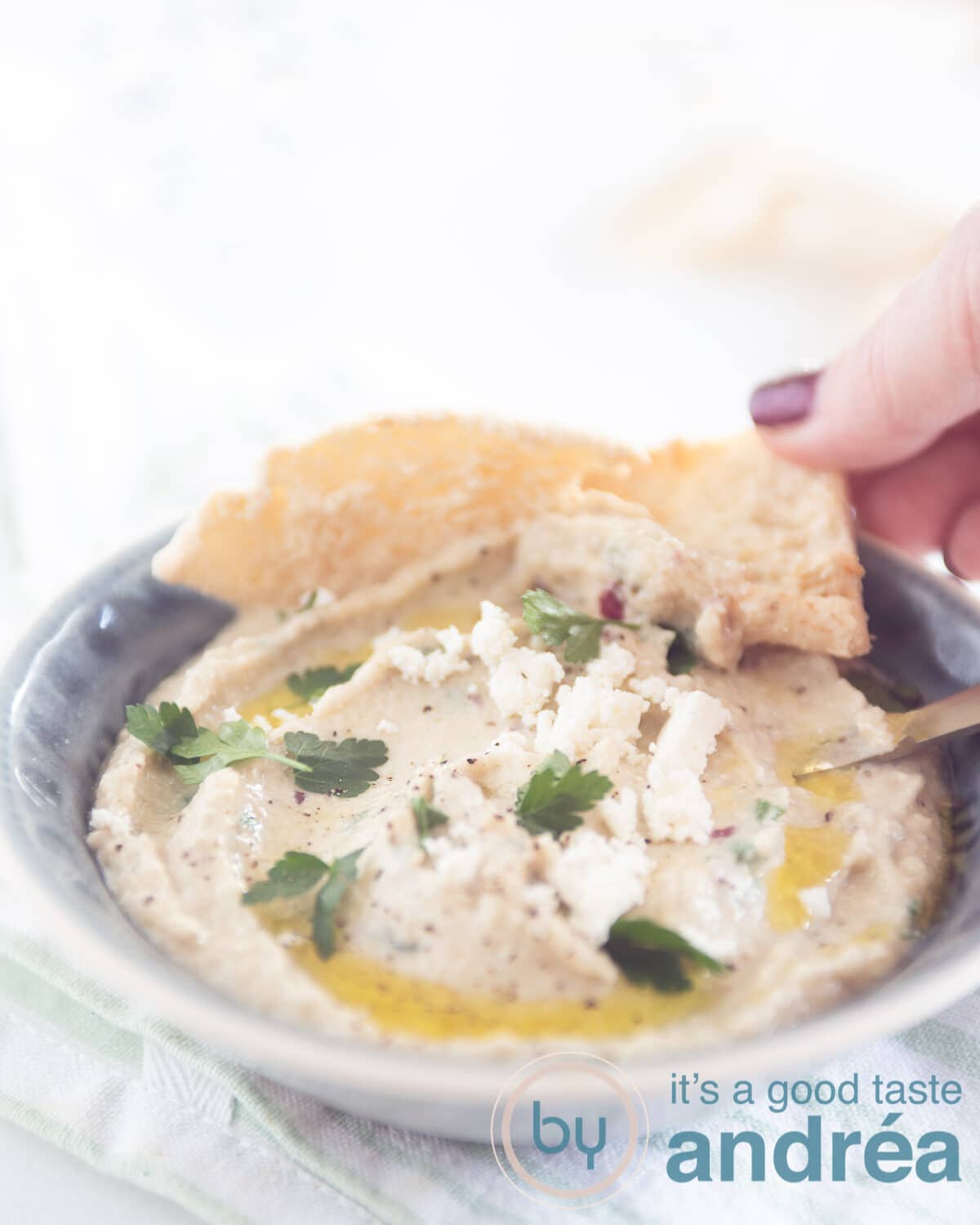 a hand taking a bite of the Melitzanosalata dip