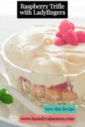 A portion of a glass bowl filled with ladyfingers, raspberries, and cream. A caption reads: Raspberry Trifle with Ladyfingers.