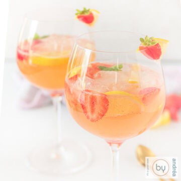A square picture with two glasses filled with strawberry gin cocktail on a white background.