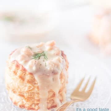 a puff pastry basket filled with shrimp gravy and topped with dill on a glass plate