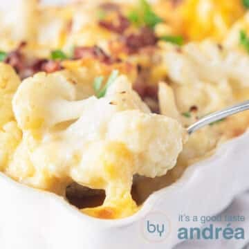 A square photo with part of a white baking dish with cauliflower, sausage from which a scoop is removed.